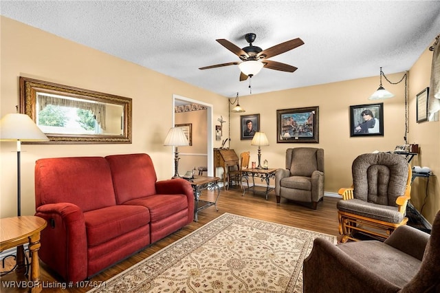 living room with ceiling fan, wood-type flooring, and a textured ceiling