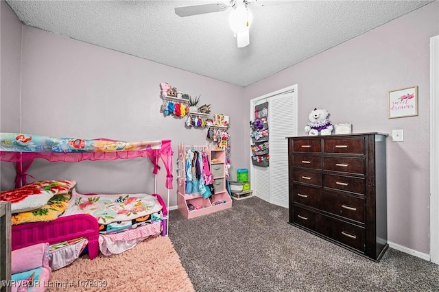 bedroom with baseboards, ceiling fan, a textured ceiling, dark carpet, and a closet