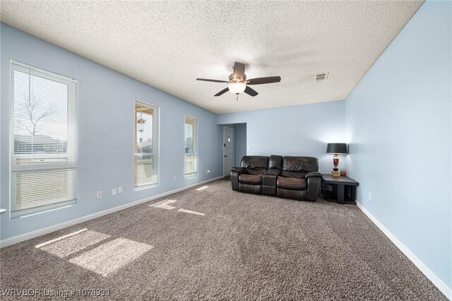 living area with a textured ceiling, carpet flooring, visible vents, a ceiling fan, and baseboards