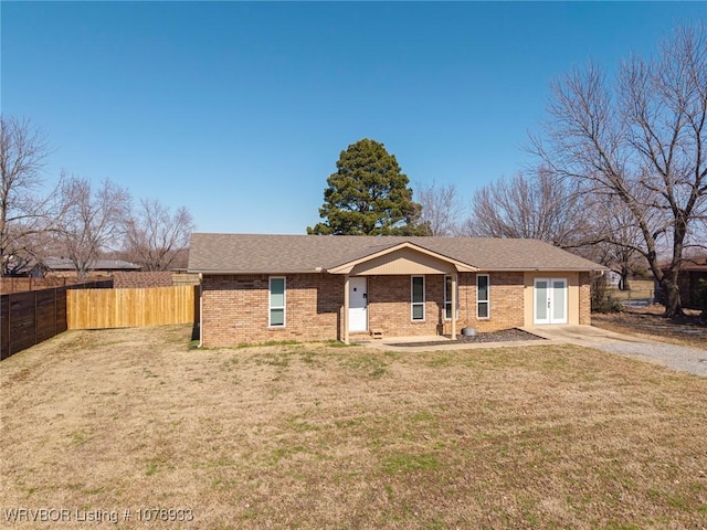 ranch-style home with a shingled roof, brick siding, fence, and a front lawn