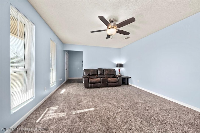 unfurnished living room with visible vents, baseboards, a ceiling fan, a textured ceiling, and carpet flooring