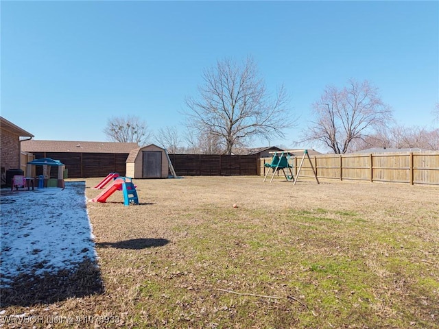 view of yard featuring a shed, a playground, a fenced backyard, and an outdoor structure