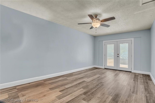 empty room featuring light wood-style floors, french doors, a textured ceiling, and baseboards