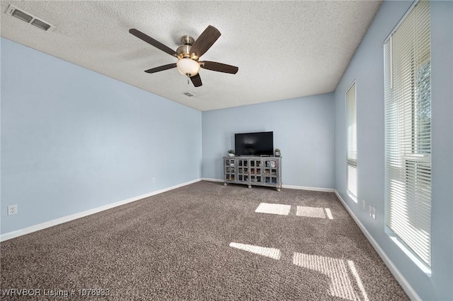 unfurnished living room featuring a textured ceiling, carpet, visible vents, and baseboards