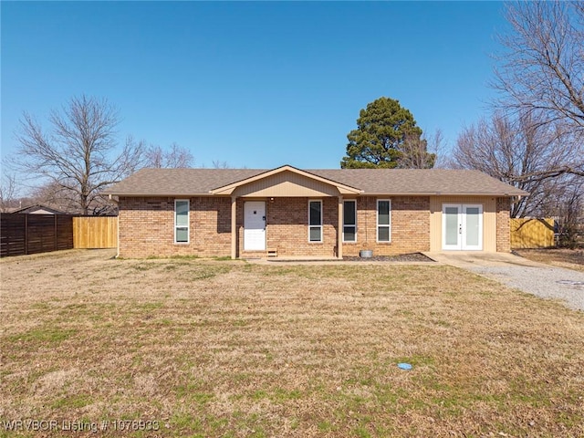 ranch-style home featuring brick siding, a front yard, fence, and french doors