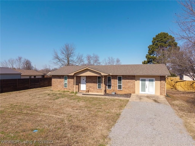 single story home featuring a shingled roof, brick siding, fence, and a front lawn