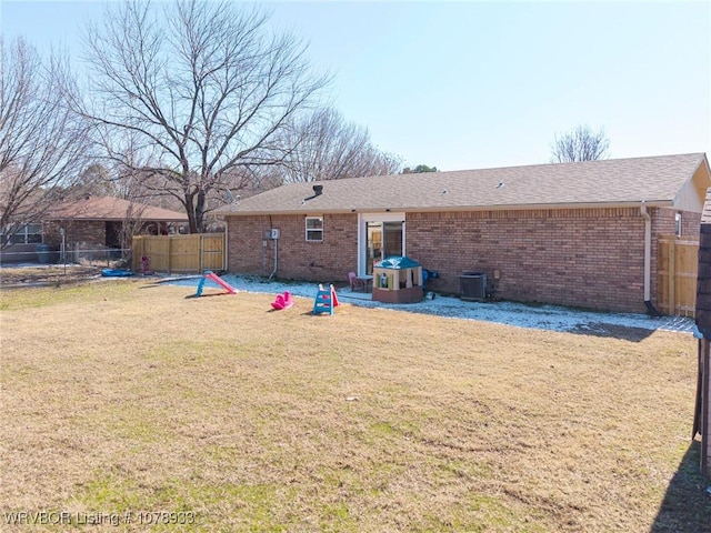 back of property featuring a yard, fence, and brick siding