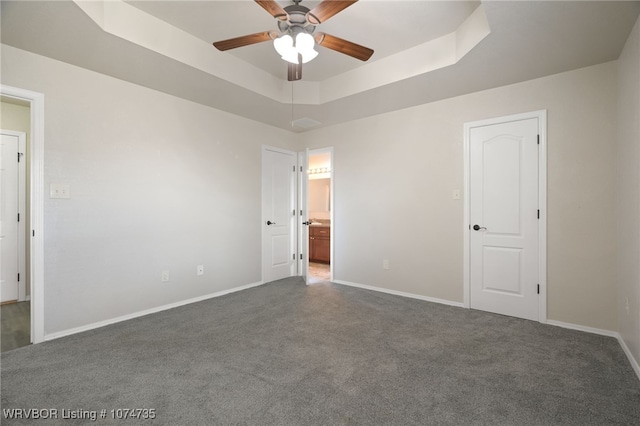 carpeted empty room with a raised ceiling and ceiling fan