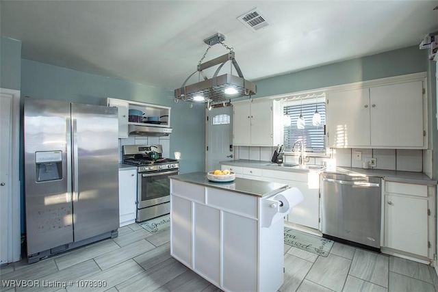 kitchen with sink, decorative light fixtures, a center island, white cabinetry, and appliances with stainless steel finishes