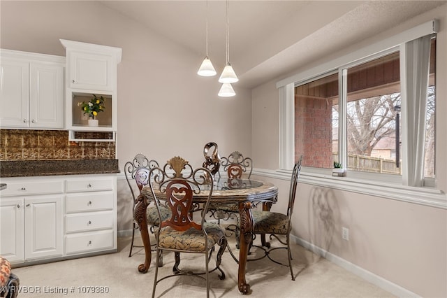 dining room featuring lofted ceiling, baseboards, and light colored carpet