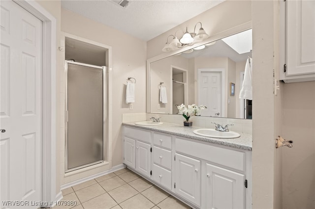 full bath featuring double vanity, tile patterned flooring, a sink, and a shower stall