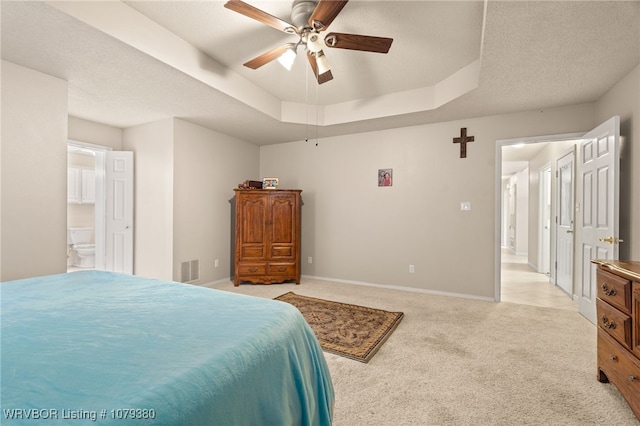 bedroom with a tray ceiling, light colored carpet, visible vents, and baseboards