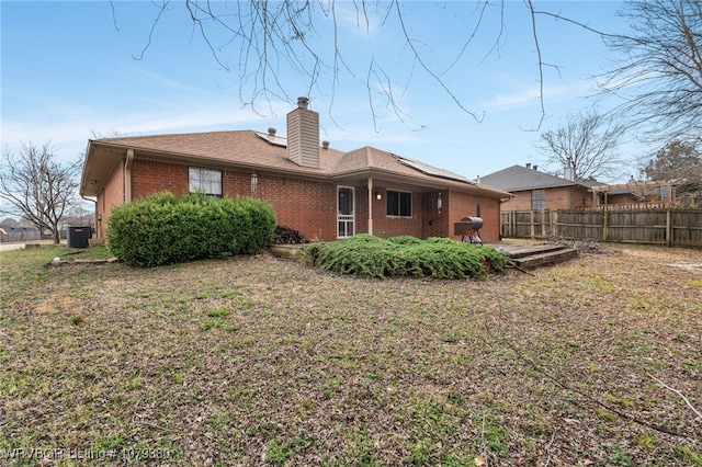 rear view of house featuring fence, a patio, brick siding, a lawn, and cooling unit