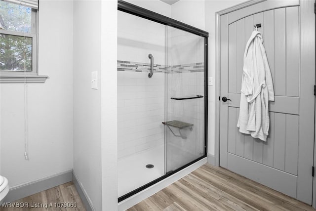 bathroom with toilet, a shower stall, baseboards, and wood finished floors