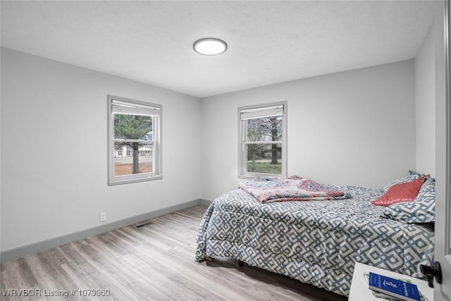 bedroom featuring wood finished floors, visible vents, and baseboards