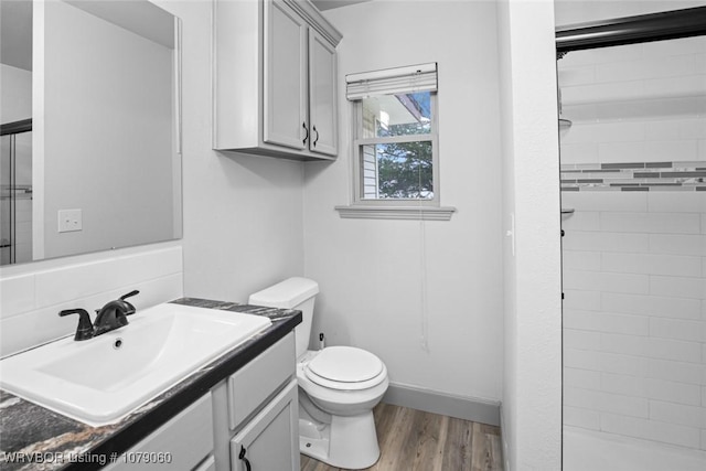 bathroom with vanity, a stall shower, wood finished floors, and toilet