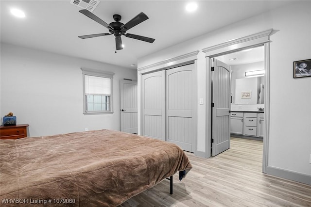 bedroom with a closet, visible vents, light wood-style flooring, ensuite bathroom, and baseboards