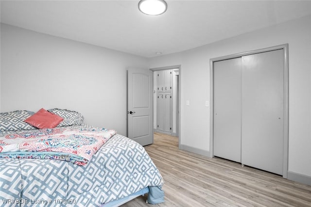 bedroom featuring a closet, wood finished floors, and baseboards