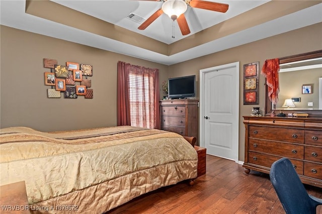 bedroom with dark wood finished floors, a raised ceiling, a ceiling fan, and visible vents