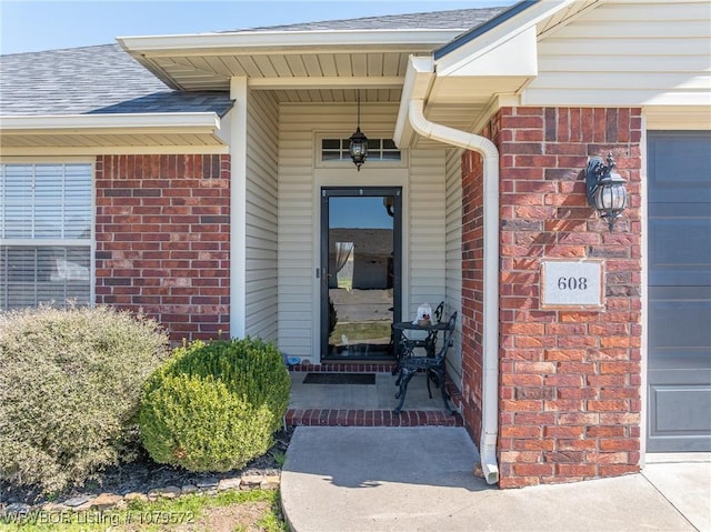 entrance to property with brick siding and roof with shingles