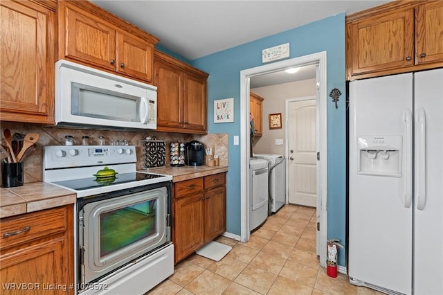 kitchen featuring white appliances, separate washer and dryer, brown cabinets, and backsplash