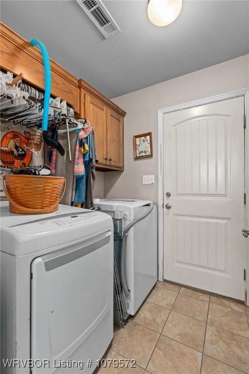 washroom featuring washer and dryer, light tile patterned floors, cabinet space, and visible vents