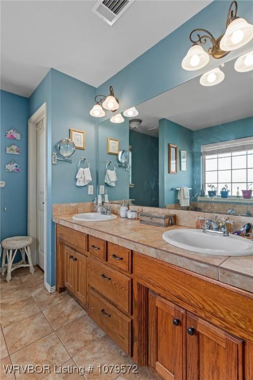 full bath featuring double vanity, visible vents, tile patterned floors, and a sink