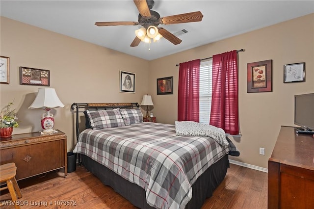 bedroom featuring ceiling fan, visible vents, baseboards, and wood finished floors