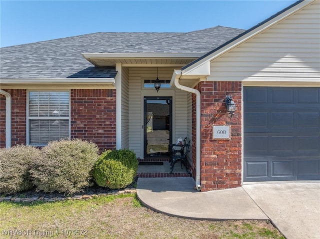 property entrance featuring a garage, brick siding, and a shingled roof