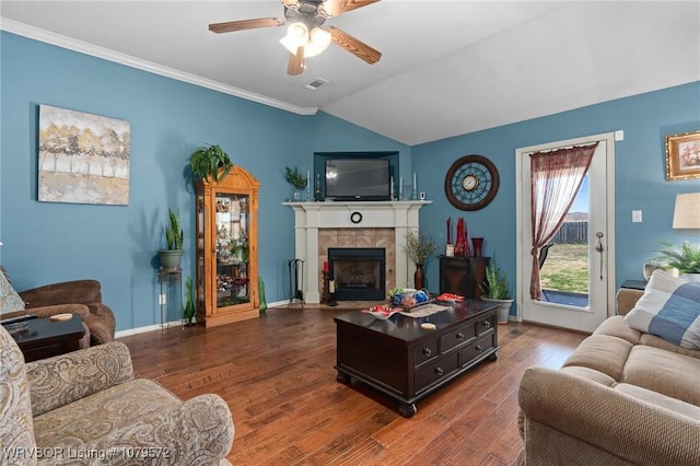 living area with visible vents, a ceiling fan, wood finished floors, lofted ceiling, and a tile fireplace