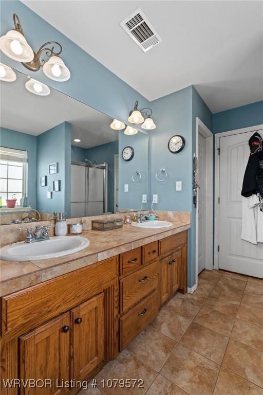 full bath featuring double vanity, visible vents, a shower stall, and a sink