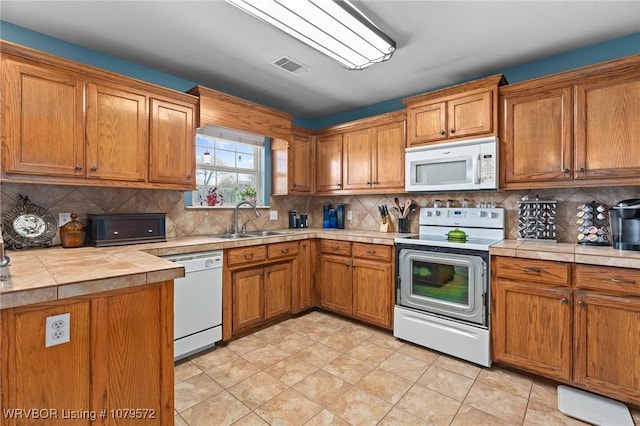 kitchen featuring white appliances, brown cabinets, visible vents, and a sink