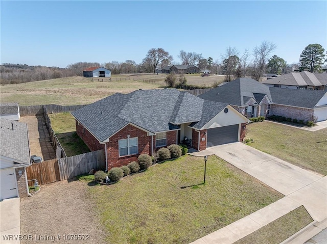 view of front facade featuring brick siding, a front lawn, fence, concrete driveway, and a garage