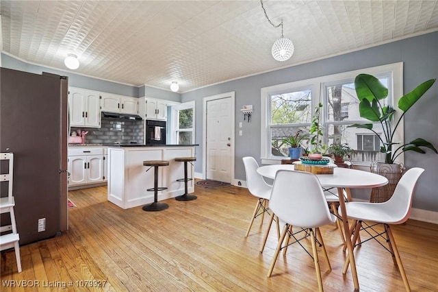 dining room with light wood finished floors, baseboards, and crown molding