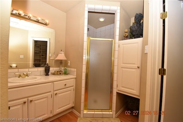 bathroom featuring hardwood / wood-style flooring, vanity, and a shower with shower door