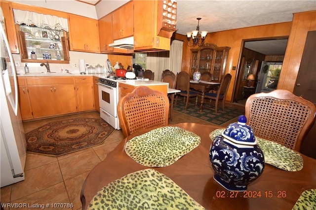 kitchen with white appliances, wooden walls, sink, a notable chandelier, and light tile patterned flooring