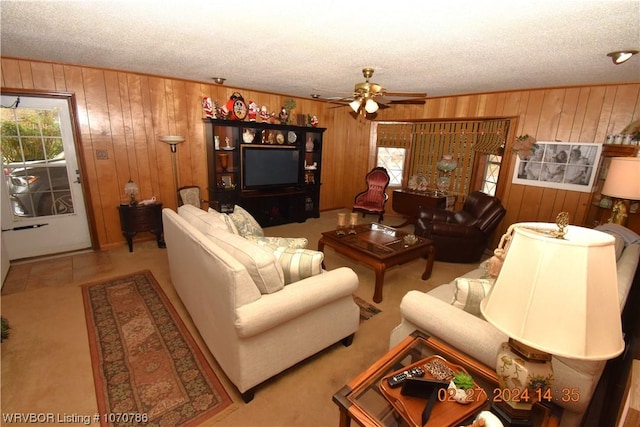 living room featuring a textured ceiling, ceiling fan, and wood walls