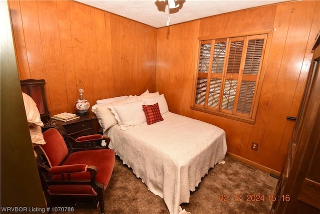 bedroom featuring dark colored carpet and wood walls