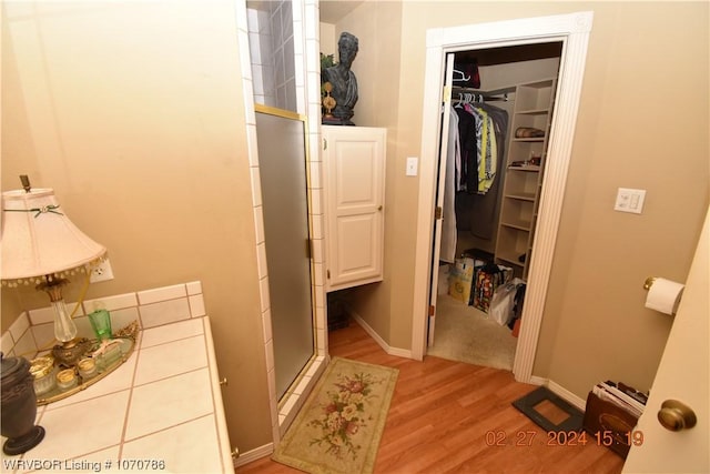 bathroom featuring a shower with shower door and wood-type flooring