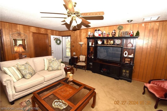 living room with light carpet, a textured ceiling, ceiling fan, and wooden walls