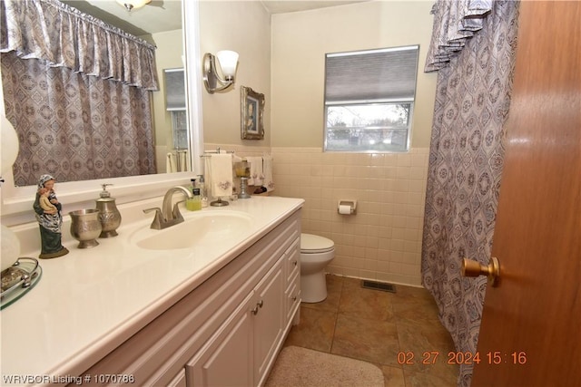 bathroom with vanity, tile walls, tile patterned flooring, toilet, and curtained shower