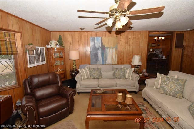 carpeted living room featuring a textured ceiling, wooden walls, and ceiling fan with notable chandelier