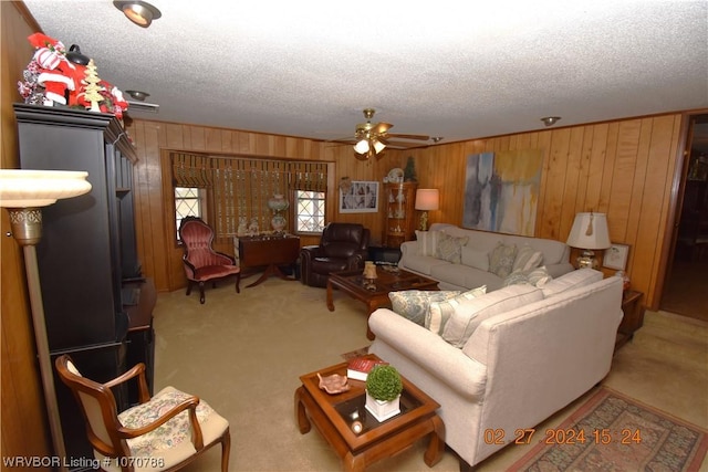 carpeted living room with ceiling fan, wood walls, and a textured ceiling