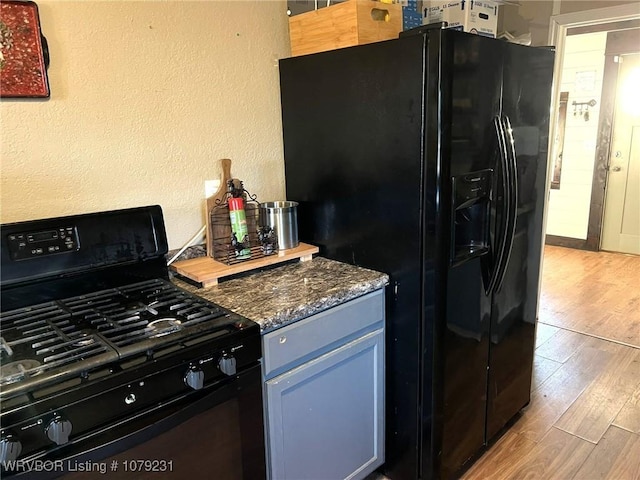 kitchen with black appliances, light wood-style flooring, and a textured wall