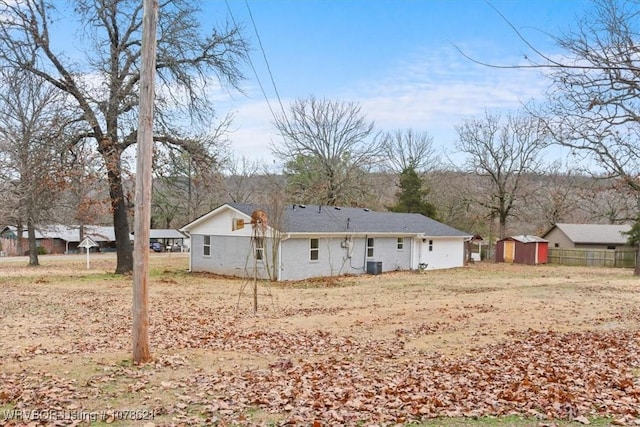 rear view of house featuring a storage shed and central AC unit