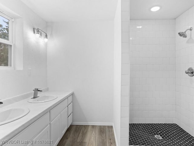 bathroom featuring vanity, wood-type flooring, and a tile shower