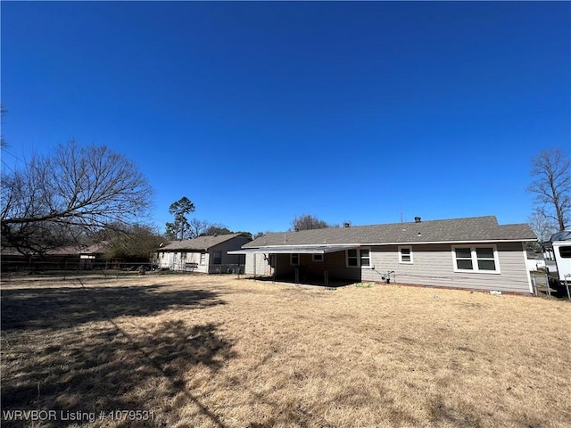 rear view of property with a yard and fence