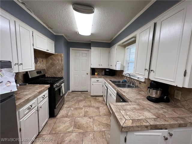 kitchen with backsplash, stainless steel range with gas cooktop, freestanding refrigerator, white cabinets, and a sink