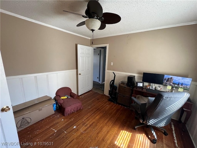 home office with a wainscoted wall, ornamental molding, wood finished floors, a textured ceiling, and a ceiling fan