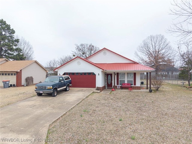 view of front facade with a porch, an attached garage, metal roof, fence, and driveway